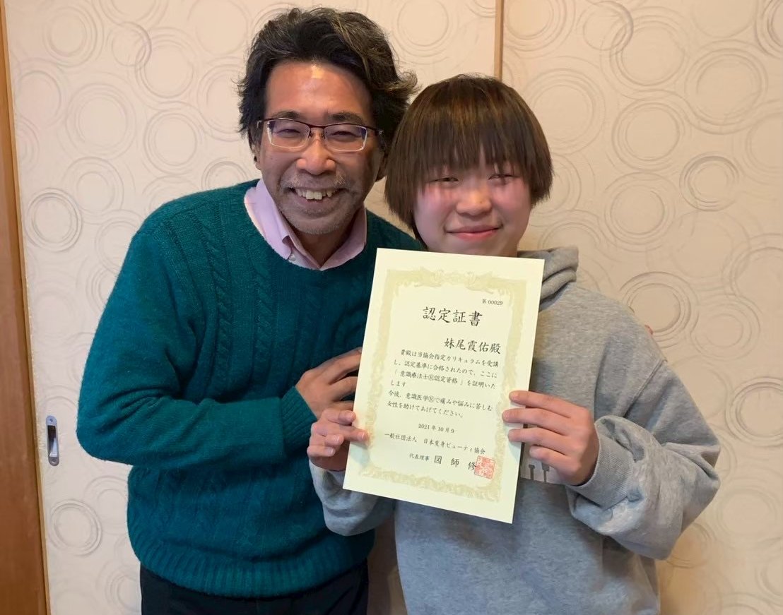 認定証書を持つ修了生と、代表理事の図師修