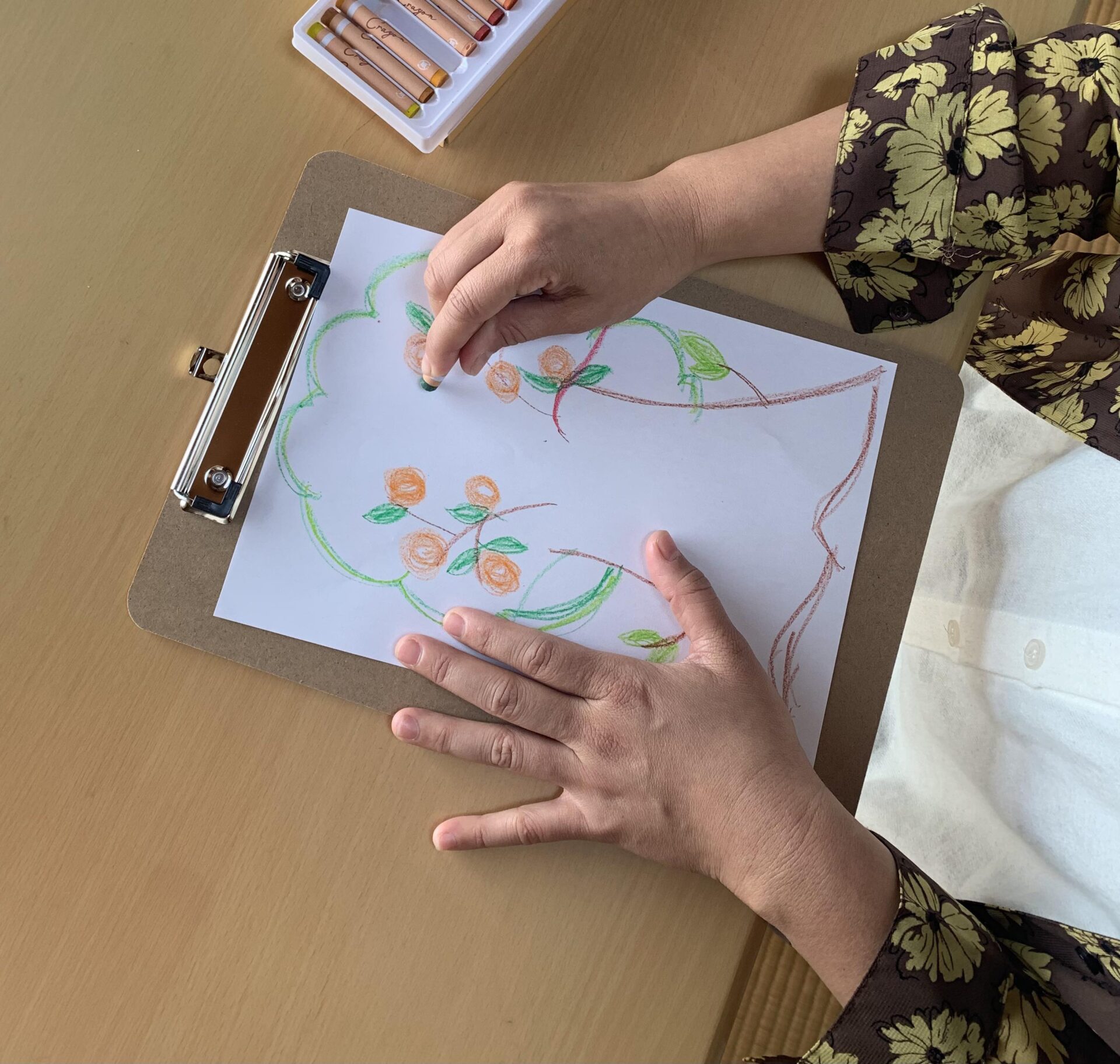 クレヨンで花の絵を描く手元の写真