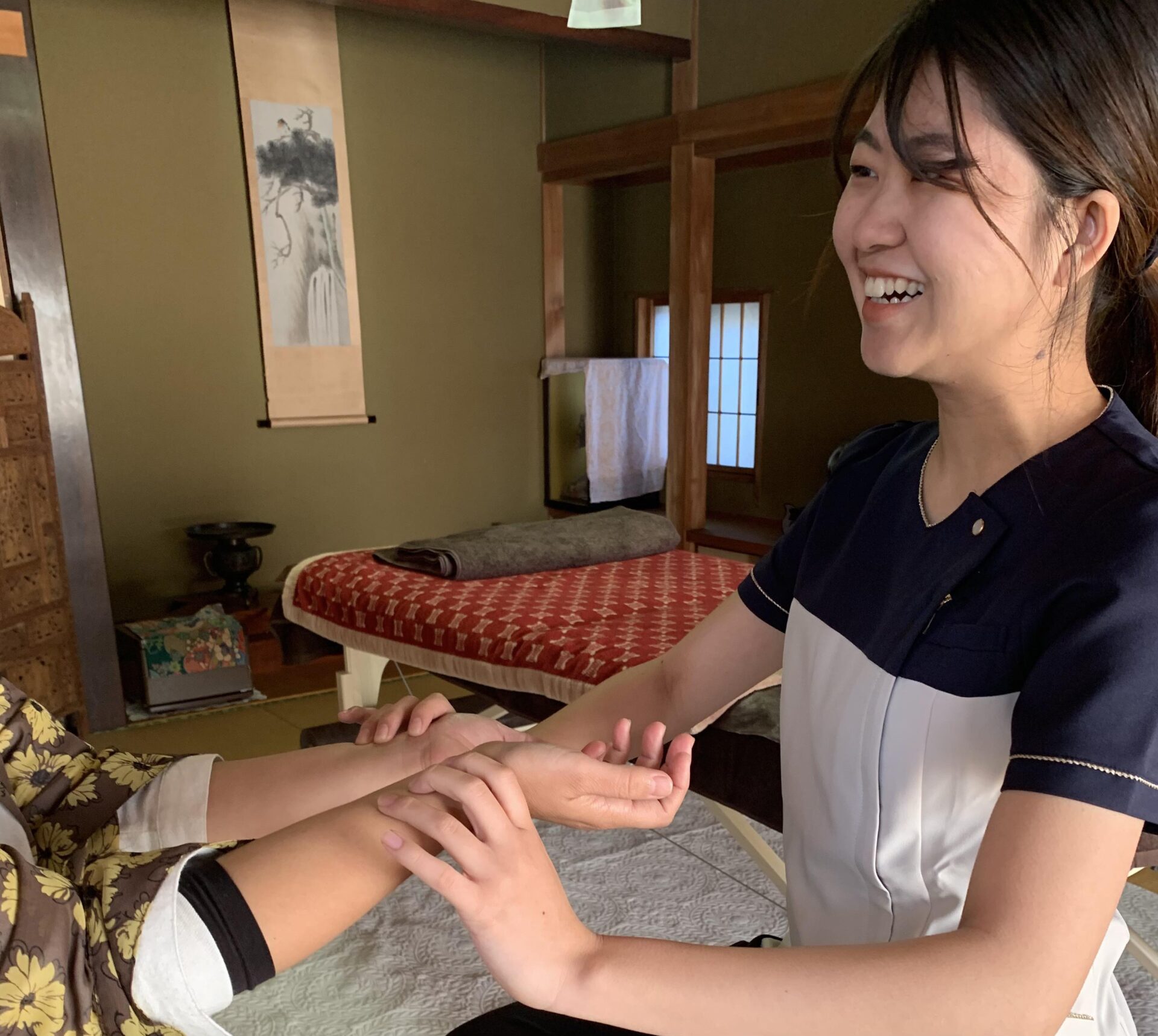 和室の施術室で笑顔で施術する様子